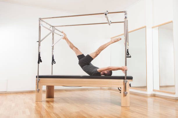 Pilates instructor performing fitness exercise on cadillac equipment, at the gym indoor