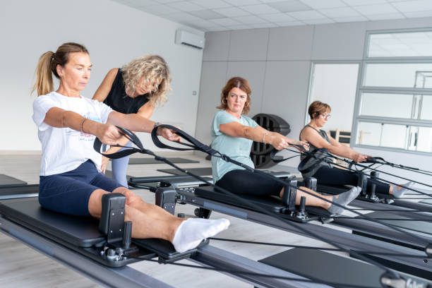 Pilates studio gym: Mature women class on reformer machine