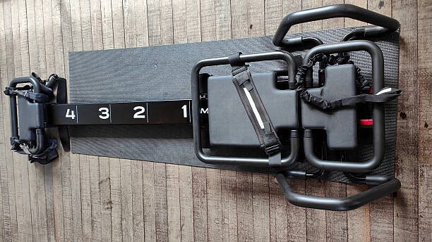 Close-up shot of Lagree Pilates  machines above wooden floors.
Concept:
Lagree Pilates studio, Lagree Pilates equipment, fitness interior, pilates class setup, modern wellness space, workout room, boutique fitness studio, pilates workout environment